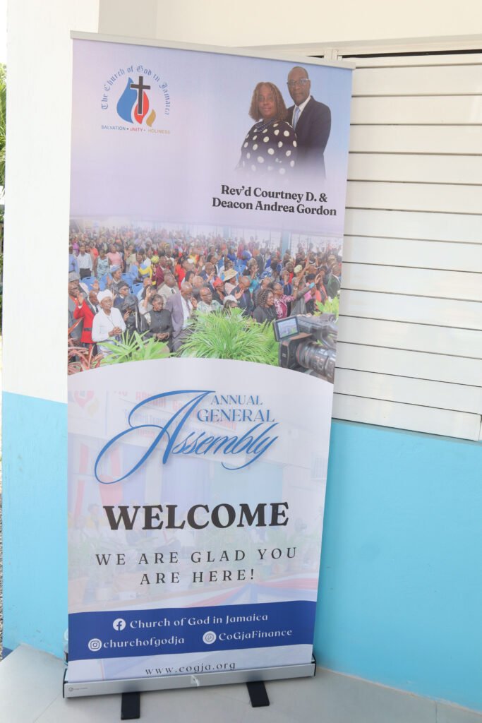 Banner for the Annual General Assembly of the Church of God in Jamaica, featuring Rev’d Courtney D. and Deacon Andrea Gordon, with a welcoming message and contact information.
